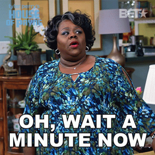 A Woman Says Oh Wait A Minute Now While Standing In A Living Room GIF