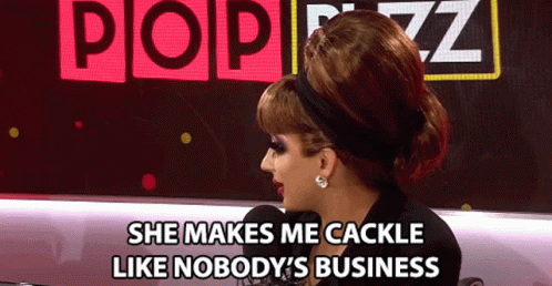 A Woman Says She Makes Me Cackle Like Nobody 'S Business In Front Of A Pop Buzz Sign GIF