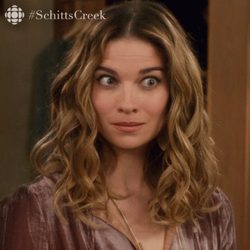 A Woman Says Sorry In Front Of A Picture Of Schitts Creek GIF