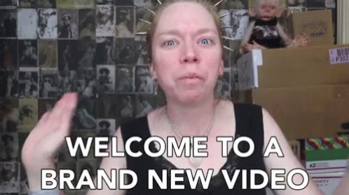 A Woman Says Welcome To A Brand New Video In Front Of Boxes GIF