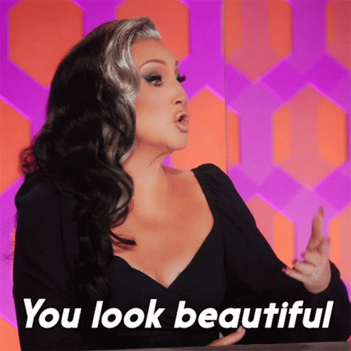 A Woman Says " You Look Beautiful " In Front Of A Purple And Orange Background GIF