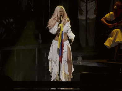 A Woman Singing Into A Microphone On Stage GIF