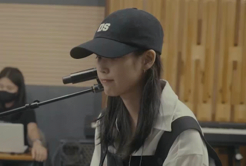 a woman singing into a microphone wearing a hat that says ds