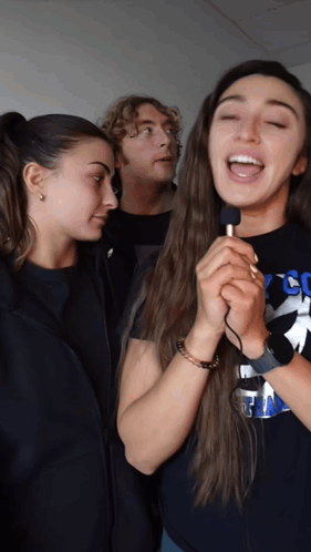 a woman singing into a microphone wearing a shirt that says cc on it