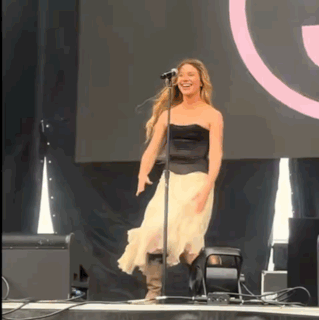 A Woman Singing Into A Microphone While Dancing On Stage GIF
