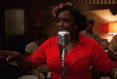 A Woman Singing Into A Microphone With A Red Shirt On GIF