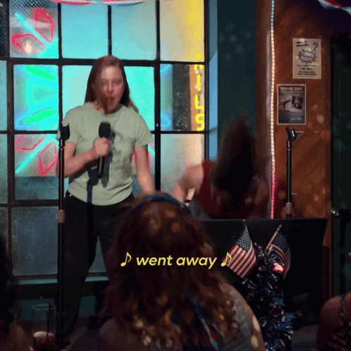 a woman singing into a microphone with a sign that says i went away