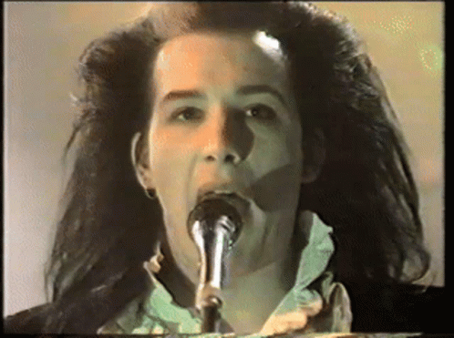 A Woman Singing Into A Microphone With Her Mouth Open GIF