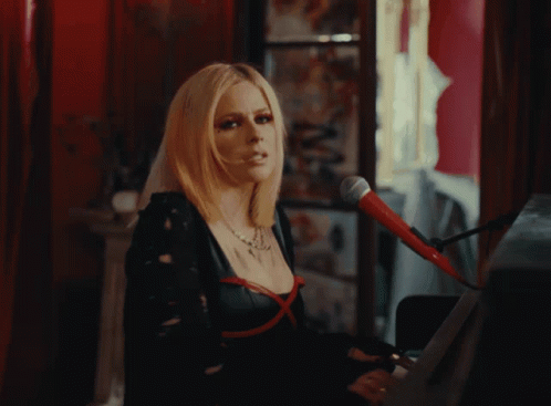 A Woman Singing Into A Microphone With Red Eye Shadow GIF
