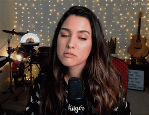 A Woman Singing Into A Microphone With The Name Kuiger On The Bottom GIF
