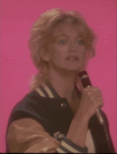 a woman singing into a microphone with the word football written below her
