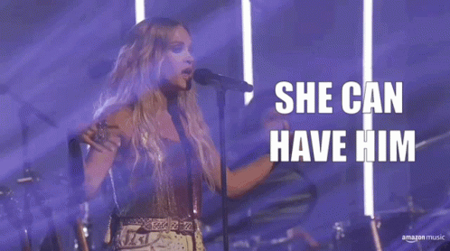 A Woman Singing Into A Microphone With The Words " She Can Have Him " Behind Her GIF