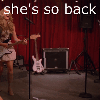 A Woman Singing Into A Microphone With The Words She 'S So Back GIF