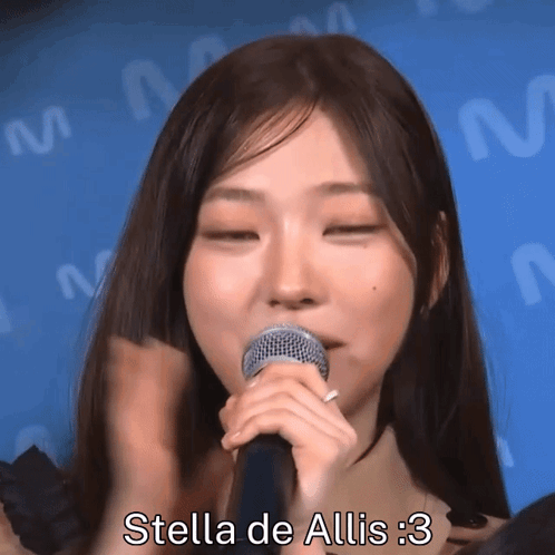 A Woman Singing Into A Microphone With The Words Stella De Allis : 3 Written Below Her GIF