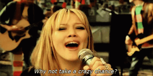 A Woman Singing Into A Microphone With The Words Why Not Take A Crazy Chance Written Below Her GIF