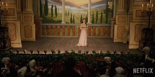 A Woman Singing On A Stage With Netflix Written On The Bottom GIF