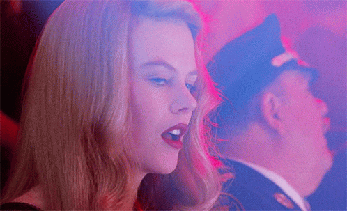 A Woman Singing With A Man In A Police Hat In The Background GIF