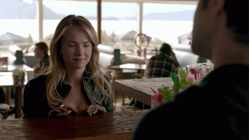 Woman Sitting At Bar Looking At Phone GIF