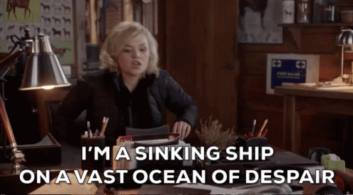 A Woman Sits At A Desk With The Words I 'M A Sinking Ship On A Vast Ocean Of Despair GIF
