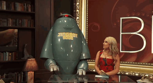a woman sits at a table next to a robot that says zioshot 9000 on it