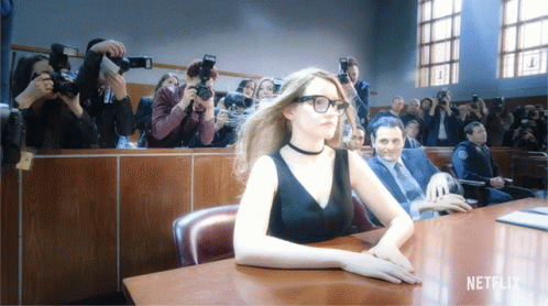 A Woman Sits At A Table With A Netflix Logo On The Bottom Right GIF