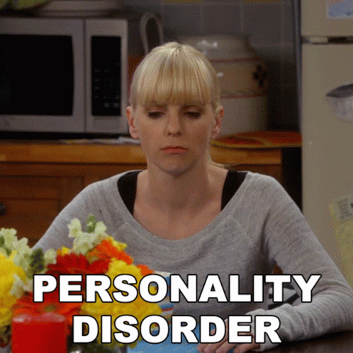 A Woman Sits At A Table With Flowers And The Words Personality Disorder Written On The Bottom GIF