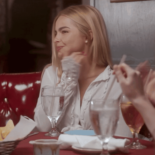 A Woman Sits At A Table With Glasses Of Water GIF