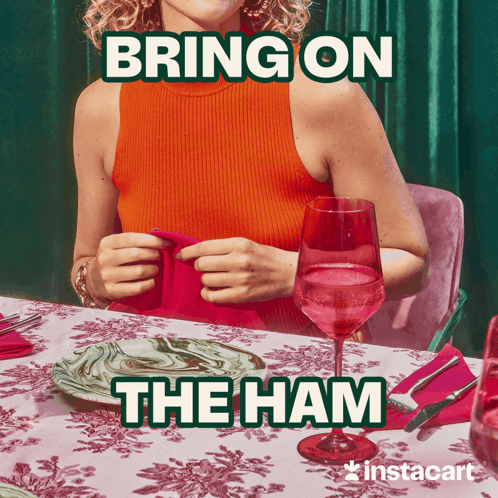 A Woman Sits At A Table With Plates And A Glass Of Wine With The Words Bring On The Ham Above Her GIF
