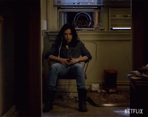 A Woman Sits In A Chair In A Room With A Netflix Logo On The Wall GIF