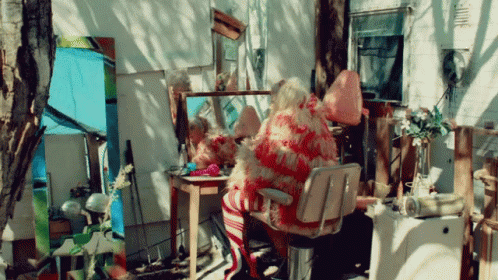 A Woman Sits In A Chair In Front Of A Mirror GIF
