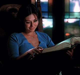 A Woman Sits In A Chair Reading A Book GIF