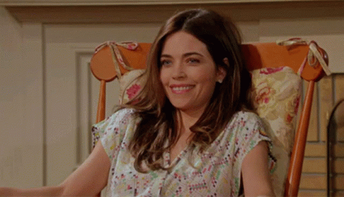 A Woman Sits In A Rocking Chair Smiling GIF