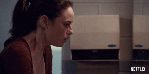 A Woman Sits In Front Of A Netflix Advertisement GIF