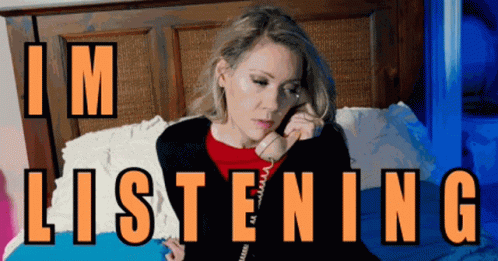 A Woman Sits On A Bed Talking On A Phone With The Words " I 'M Listening " Written Above Her GIF