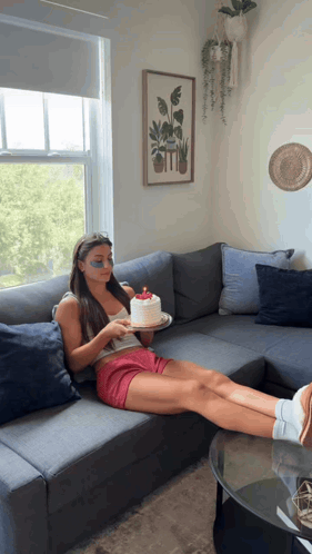 a woman sits on a couch holding a cake