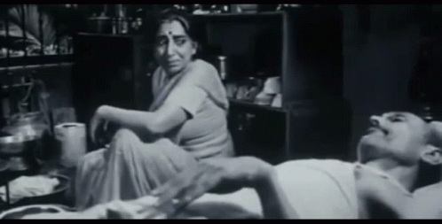 A Woman Sits On The Floor Next To A Man Laying On The Floor GIF