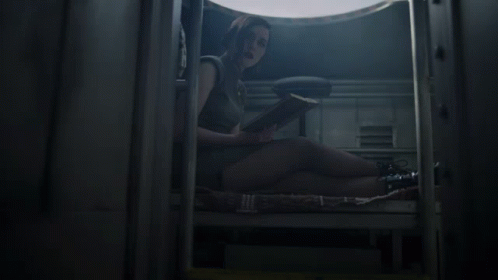 A Woman Sits On The Floor Reading A Book In A Dark Room GIF