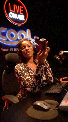 A Woman Sitting At A Desk In Front Of A Sign That Says Live On Air GIF