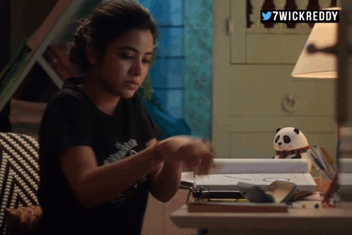 A Woman Sitting At A Desk With 7Wickreddy Written On The Top Right GIF