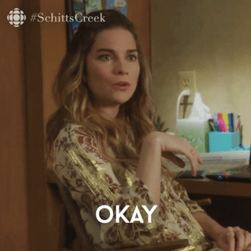 A Woman Sitting At A Desk With The Word Okay Written On The Screen GIF