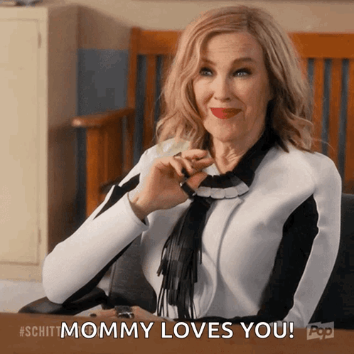 A Woman Sitting At A Desk With The Words " Mommy Loves You " Above Her GIF