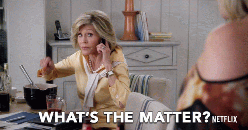 A Woman Sitting At A Table Talking On A Cell Phone With The Words What 'S The Matter Netflix Behind Her GIF