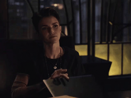 A Woman Sitting At A Table With A Blue Folder In Front Of Her GIF