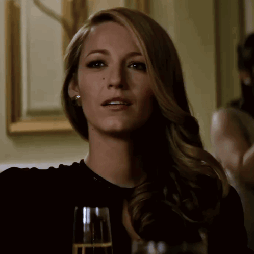 A Woman Sitting At A Table With A Glass Of Champagne GIF