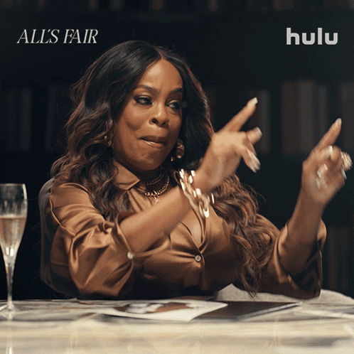 A Woman Sitting At A Table With A Glass Of Champagne And Hulu Written On The Bottom GIF