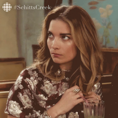 Woman Sitting At Table With Juice And Schitts Creek Logo GIF