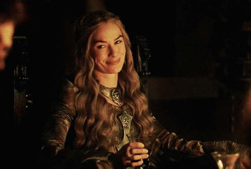 A Woman Sitting At A Table With A Glass Of Wine GIF