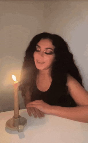 A Woman Sitting At A Table With A Lit Candle GIF