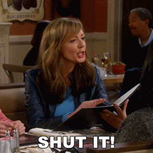 A Woman Sitting At A Table With A Menu And The Words Shut It On The Table GIF