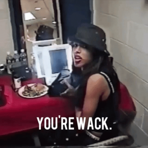 A Woman Sitting At A Table With A Plate Of Food And The Words " You 'Re Wack " GIF